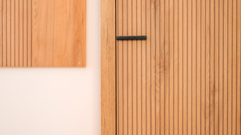 Close-up of fluted wooden door with a black handle
