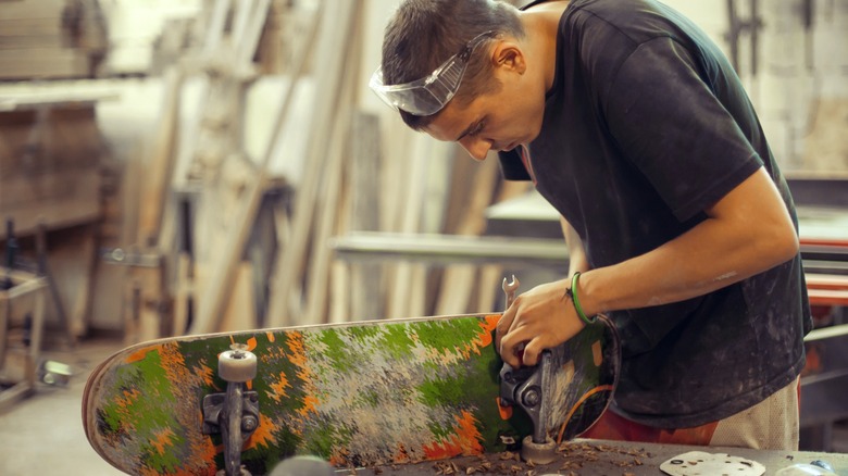 Person removing trucks from skateboard to repurpose deck