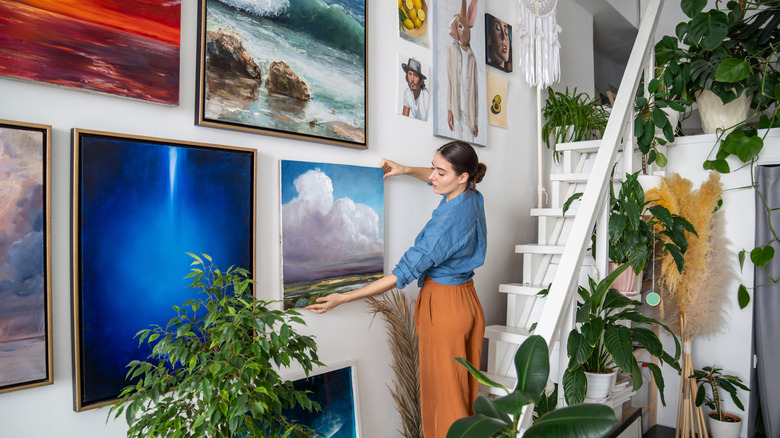 Woman hangs pictures on wall