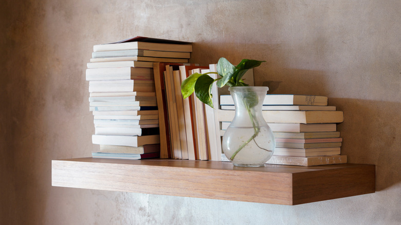 Books are stacked on a floating wood shelf