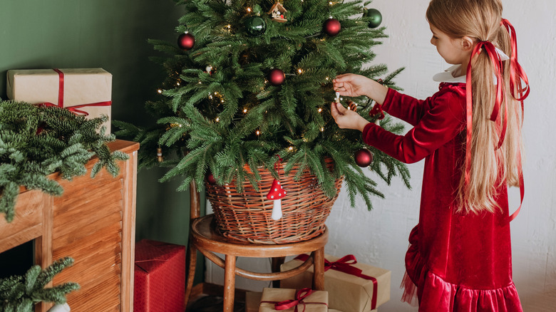 Little girl hanging ornament on tree