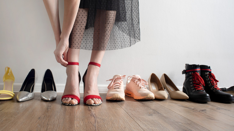 woman taking off red shoes and more pairs on floor