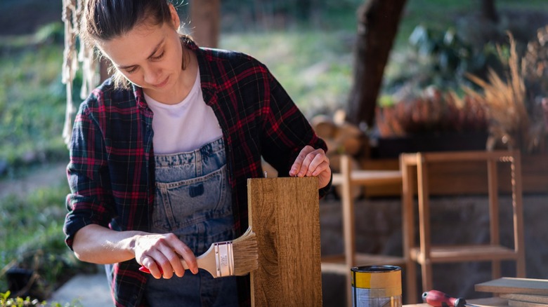 person staining wood shelf