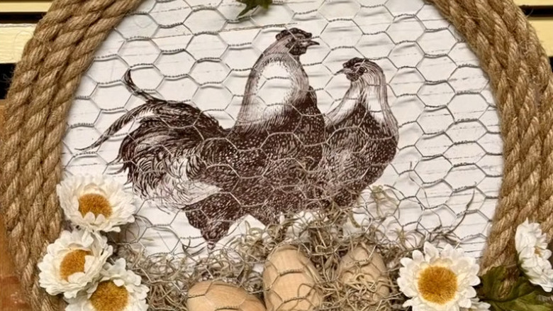 Chicken-themed pizza pan wall art with chicken wire and fake flowers.