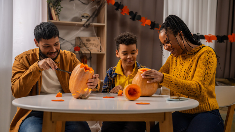 family craving pumpkins at table