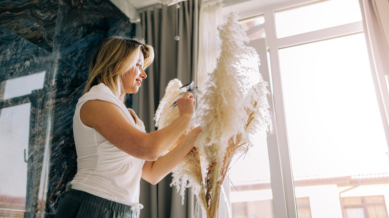 woman arranging pampas grass in vase