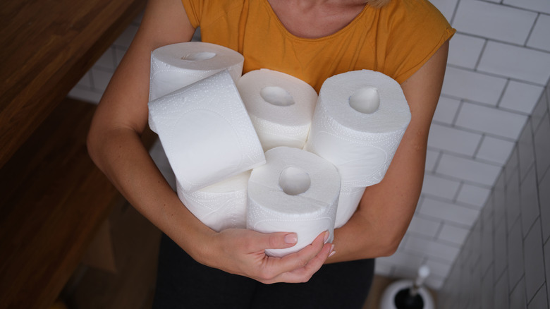 woman holding toilet paper rolls