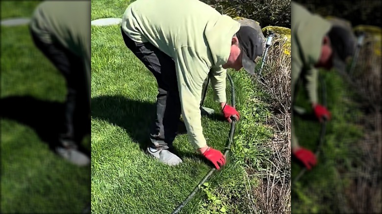 Man measuring pipe on grass