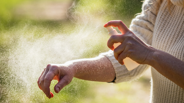 Person applying mosquito repellent to arm