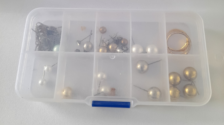 Close up of clear compartment organizer filled with jewelry pieces