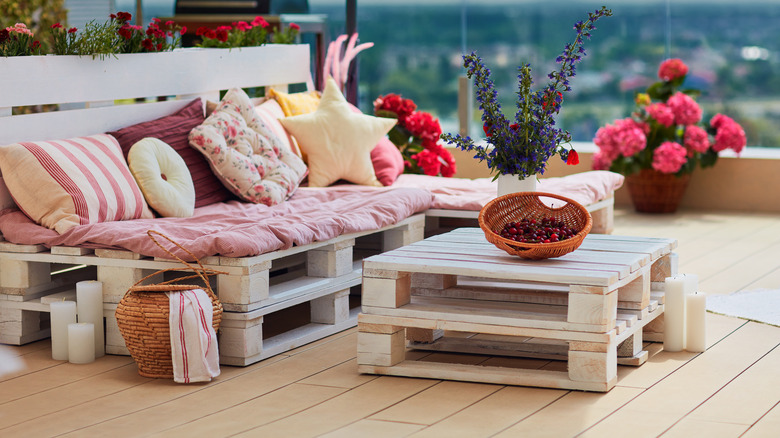 Pallet furniture; bench with pink upholstery and pillows, basket on the table