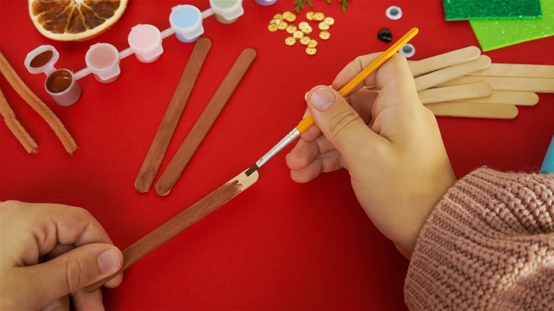 Person painting wooden popsicle sticks.