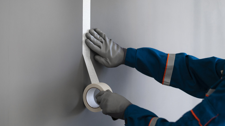 Worker laying down painters' tape.