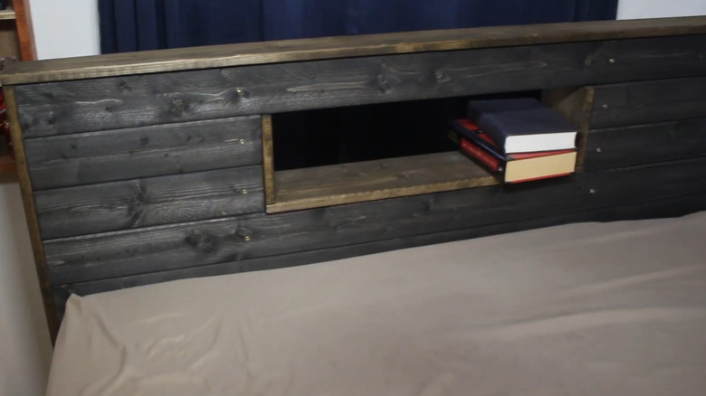 A headboard with a hole carved out of the middle to serve as a shelf for books.