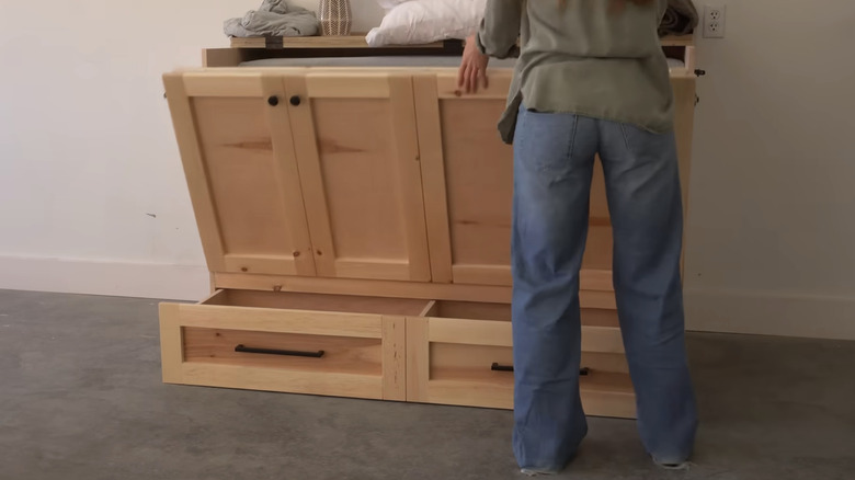 A woman opening a wooden sideboard