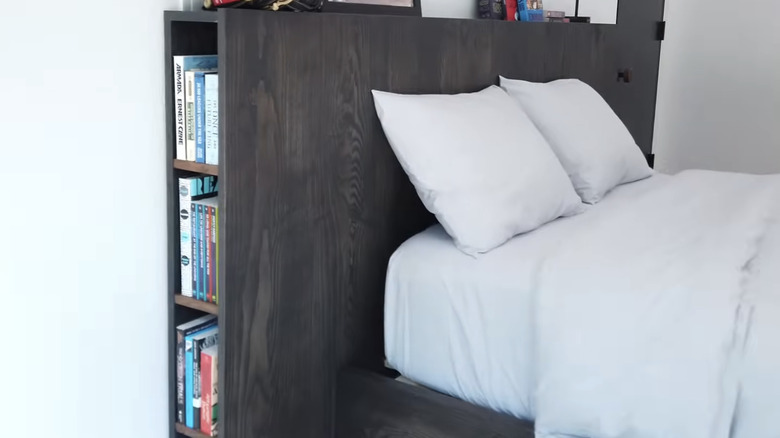 A bed with a bookshelf integrated into the headboard.
