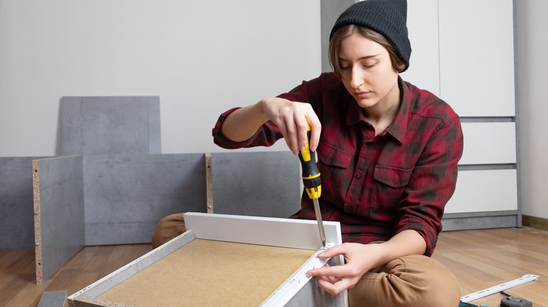 A person assembling a drawer in a bedroom