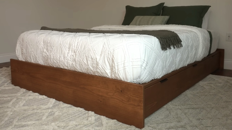 A wooden platform bed with drawers.