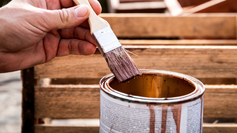 A DIYer gets ready to apply wood stain to a pallet