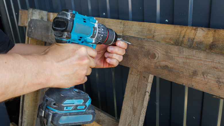 A person uses a power tool to make a DIY with a wooden pallet