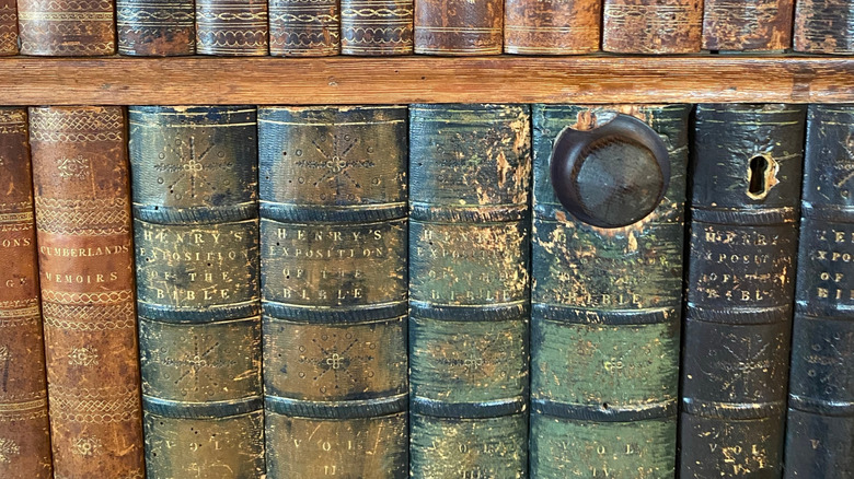 A knob and key hole in a DIY hidden library door covered in trimmed book spines.