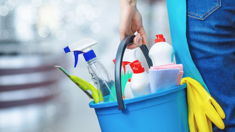 person carrying cleaning products bucket
