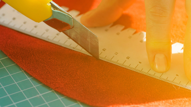 Person cutting red leather