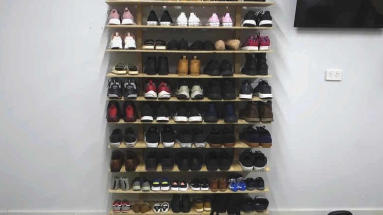 Wall mounted shoe storage shelves on a white wall with a mounted TV