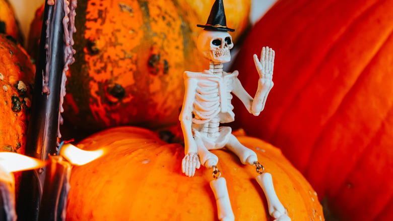 Toy skeleton sitting on pumpkin.