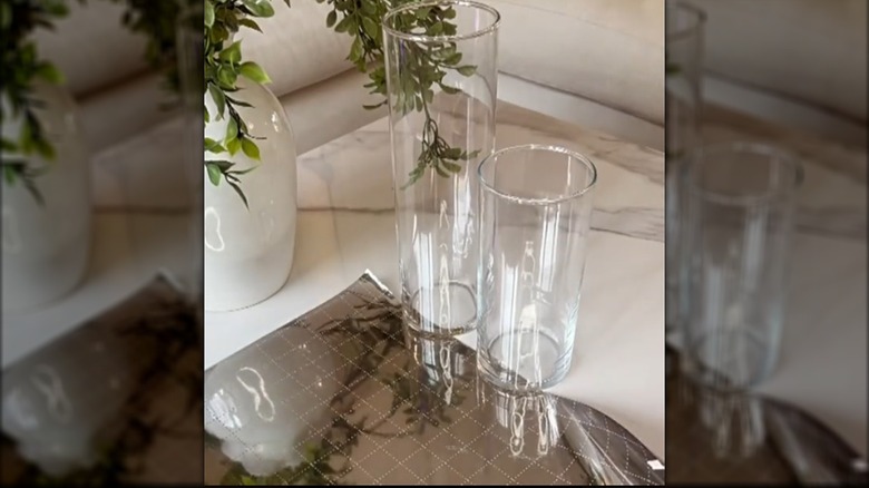 Two clear glass cylinder vases and a roll of privacy film sitting on a table