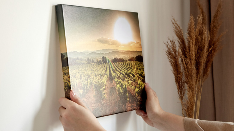 person holds a canvas print against a wall