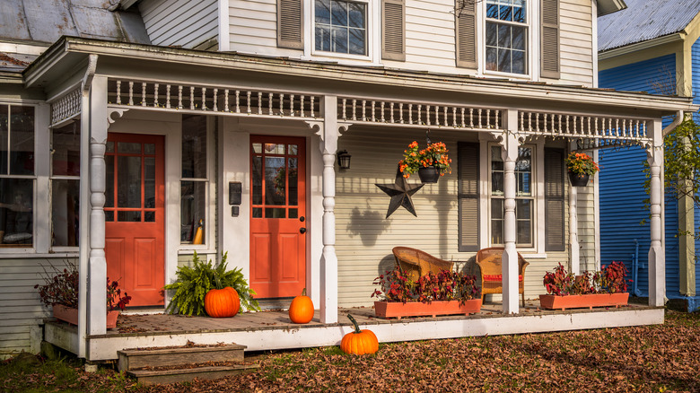 Charming old house during autumn with orange doors, decorated with pumpkins for fall season and Halloween. Photo taken in Montgomery Center, Vermont, New England, United States in October 2023.