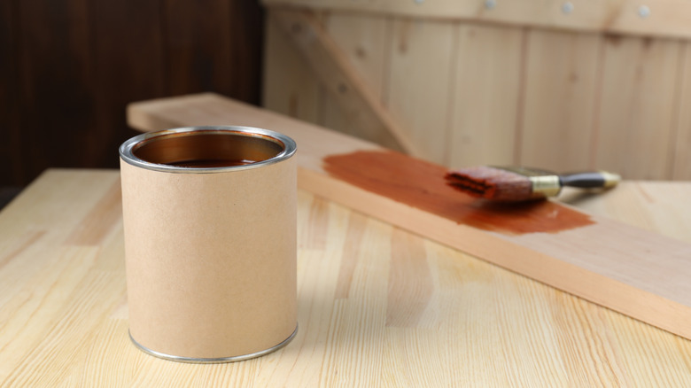 Can and brush with wood stain on wooden surface