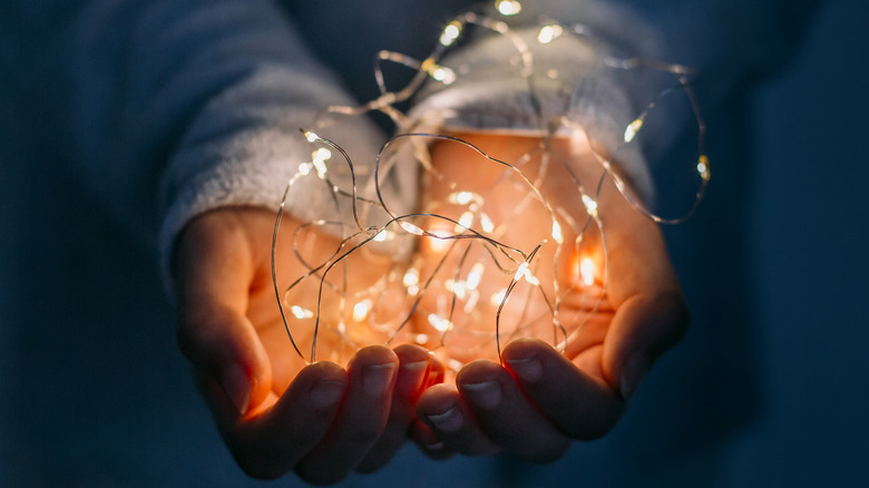 A person holding tangled fairy lights on wire