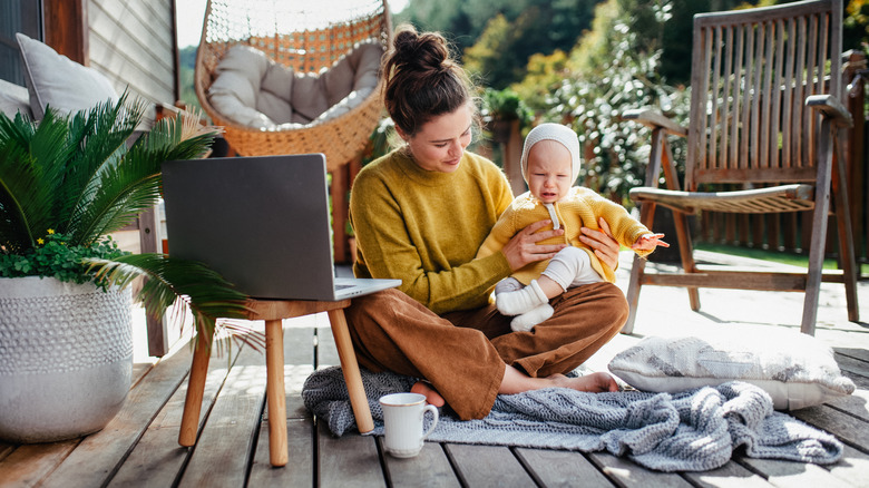 Mother and baby on a patio with computer and beverage
