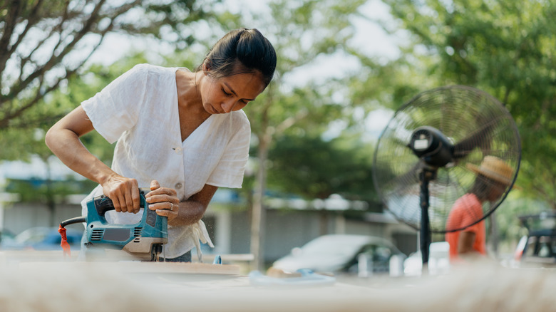 Homeowner using a jigsaw in her driveway