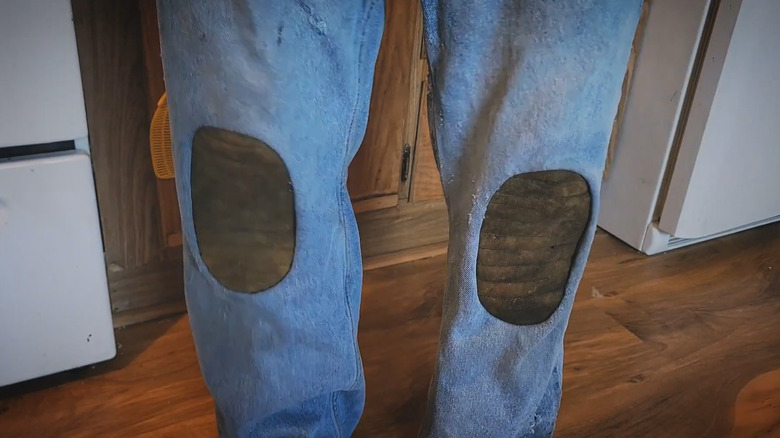 Person wearing old jeans with knee pads added in