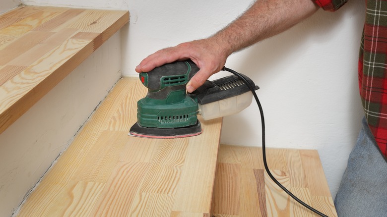 closeup of man sanding stair tread