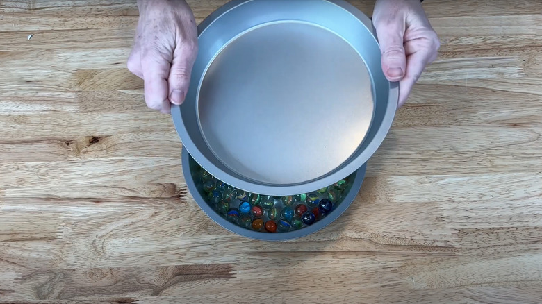A person assembling a DIY lazy Susan with cake pans.