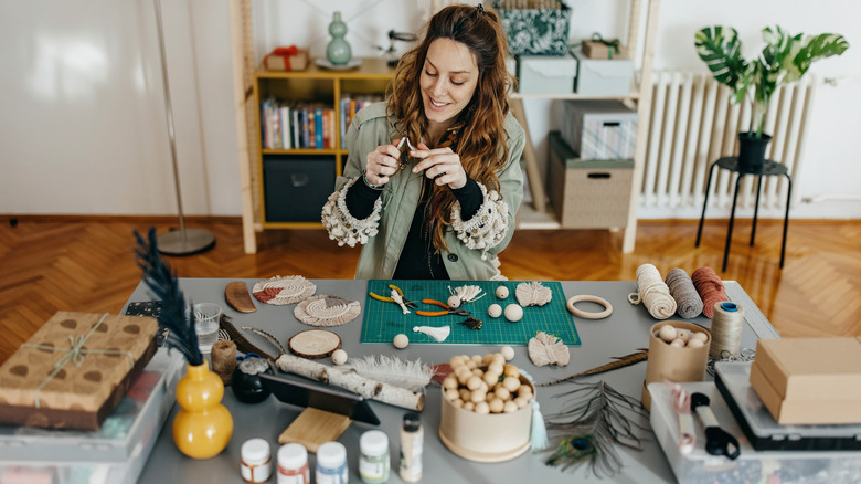 A woman works on a DIY project at a table