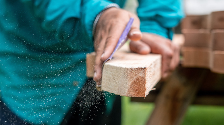 Person's hands sanding a cedar plank