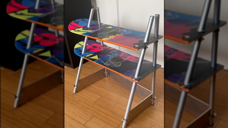 A DIY two-level shelf on the floor made from two halves colorful snowboard and a metal frame
