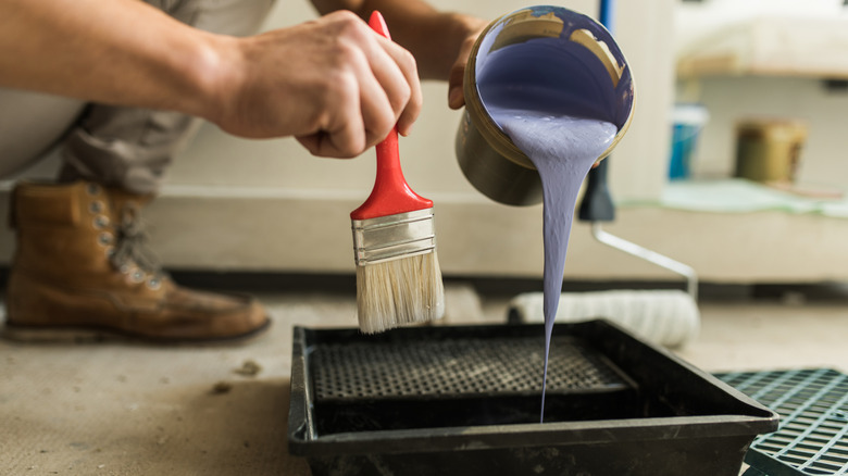 Person pours purple paint before decorating their sliding closet door.