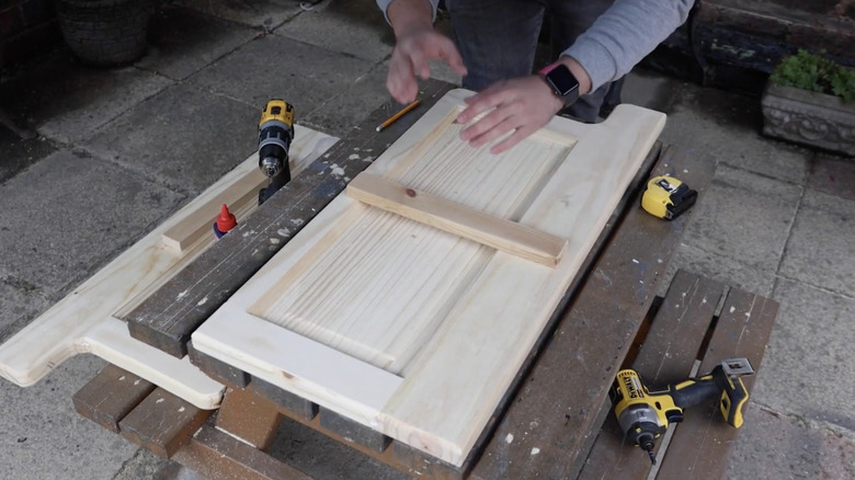 A wooden beam laid on top of part of a wooden door with tools surrounding it