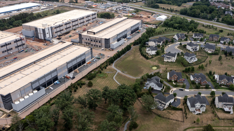 A large data center is shown next to several residential homes