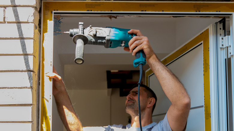 Man replacing front door of house