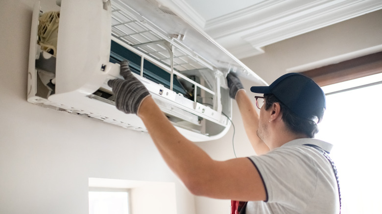A man repairs a wall-mounted air conditioning unit