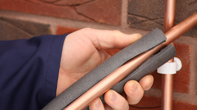 a hand holding pipe and insulator