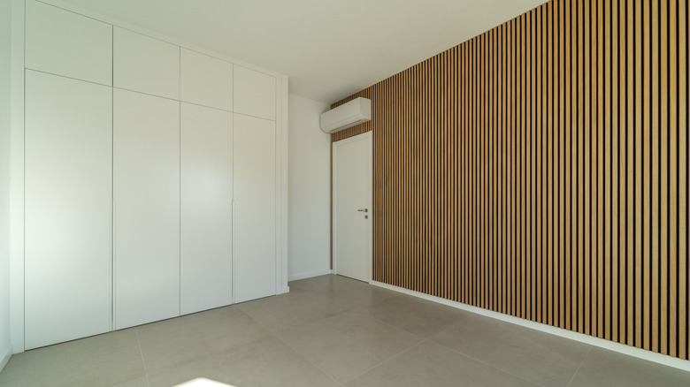 An empty bedroom has a wall of wooden acoustical panels