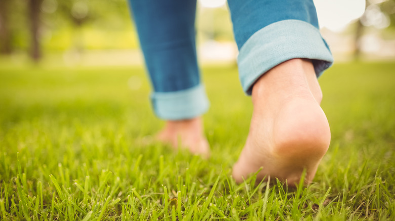 A woman is walking barefoot on her lawn